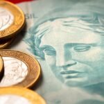 Moedas brasileiras sobre nota de Real, com foco em RPVs.